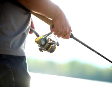 Person holding a fishing rod near the water.