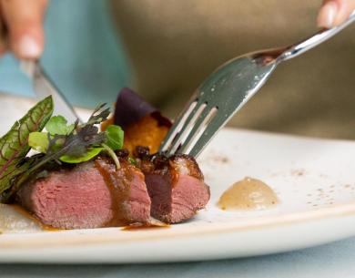 Saftiges Fleisch mit Sauce und Gemüse auf einem eleganten Teller.