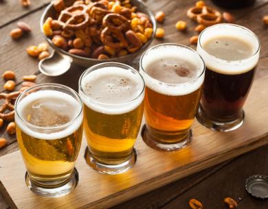 Dégustation de bières artisanales avec des snacks salés sur une planche en bois.