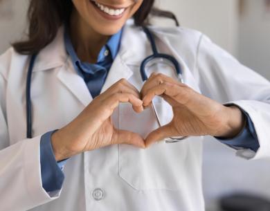 Doctor with stethoscope forms a heart with hands.