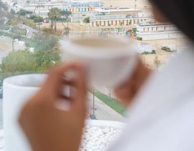 Vista sul mare con una tazza di caffè in mano.