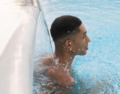 Person in a pool under a waterfall.