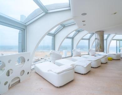 Salle de détente avec vue sur la mer et chaises longues blanches.