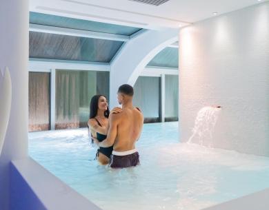 Couple heureux dans une piscine intérieure avec cascade.