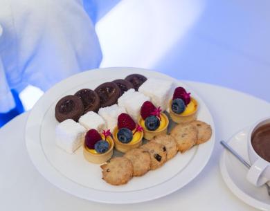 Assorted desserts and hot chocolate on a table with a candle.