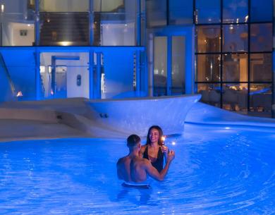 Couple dans la piscine avec lumières bleues, ambiance romantique.