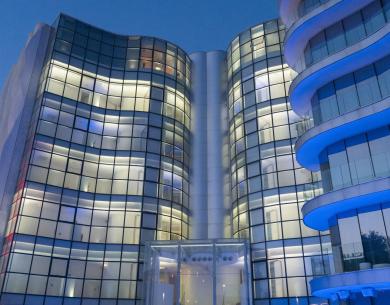 Bâtiment moderne avec façades vitrées et lumières bleues la nuit.