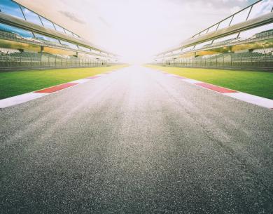 Empty racetrack with grandstands at sunset.