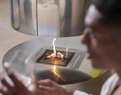 Man in a robe near a modern fireplace.