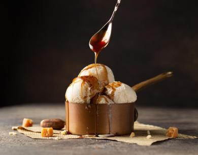 Gelato alla vaniglia con salsa al caramello in una ciotola di rame.