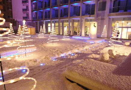 Snowy courtyard with light trees in front of a building.