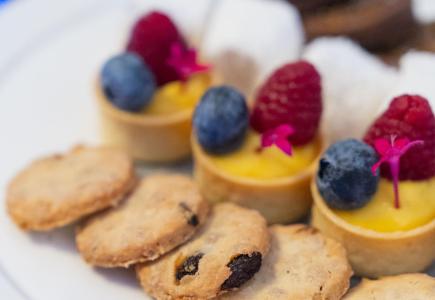 Assorted desserts with berries and cookies on a white plate.