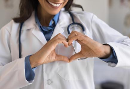 Doctor with stethoscope forms a heart with hands.