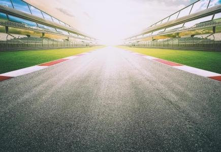 Empty racetrack with grandstands at sunset.