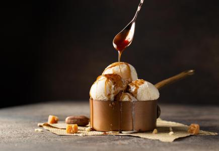 Gelato alla vaniglia con salsa al caramello in una ciotola di rame.