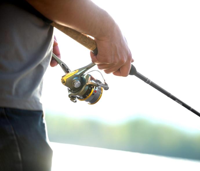 Person holding a fishing rod near the water.