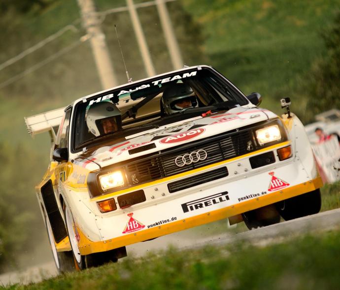 Auto da rally Audi in azione su una strada sterrata.