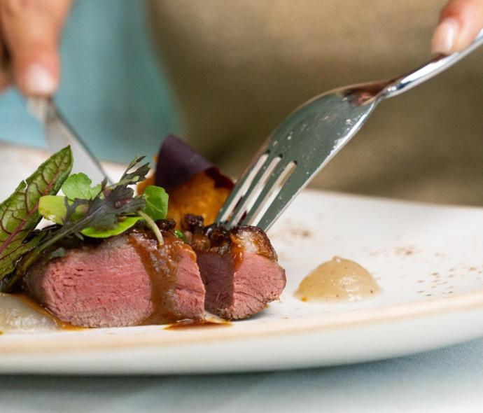 Saftiges Fleisch mit Sauce und Gemüse auf einem eleganten Teller.