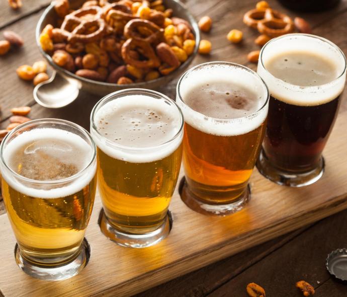 Dégustation de bières artisanales avec des snacks salés sur une planche en bois.