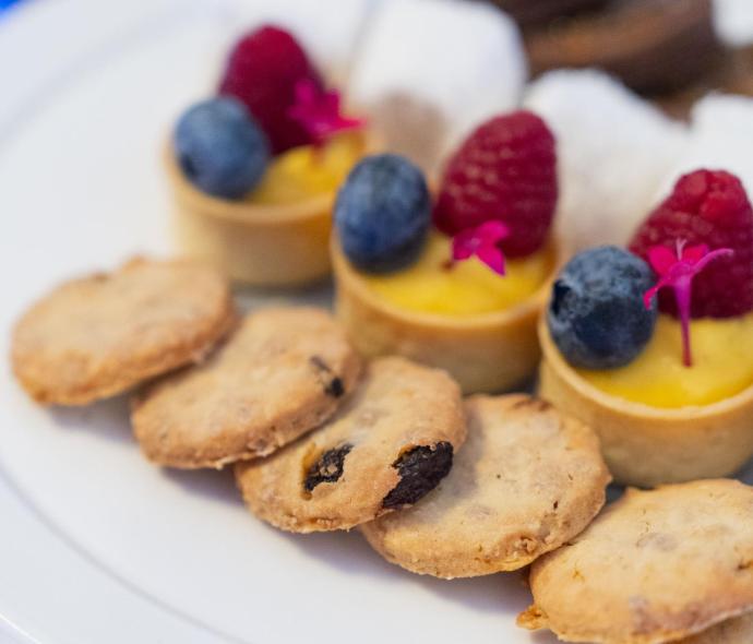 Dolci assortiti con frutti di bosco e biscotti su un piatto bianco.