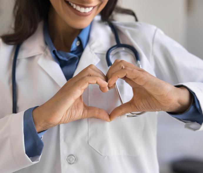 Doctor with stethoscope forms a heart with hands.