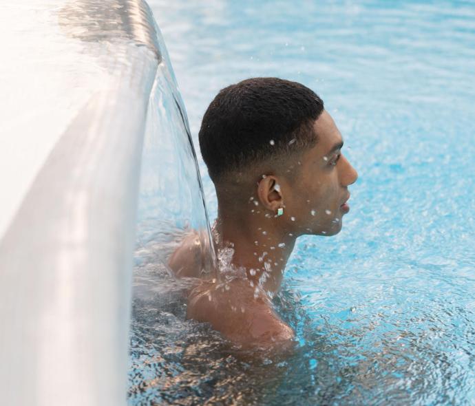 Person in a pool under a waterfall.