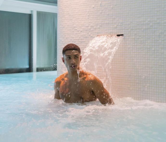 Homme dans une piscine sous une cascade.