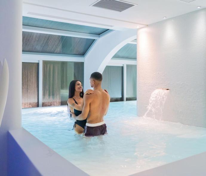 Couple heureux dans une piscine intérieure avec cascade.