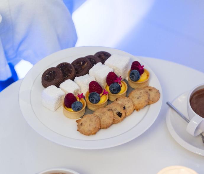 Assorted desserts and hot chocolate on a table with a candle.