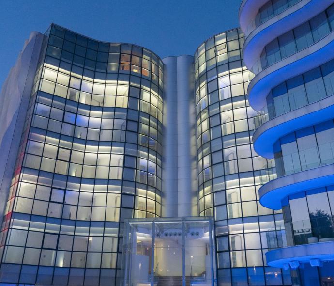 Modern building with glass facades and blue lights at night.