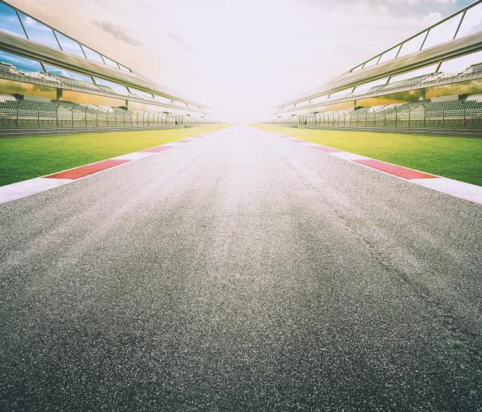 Empty racetrack with grandstands at sunset.