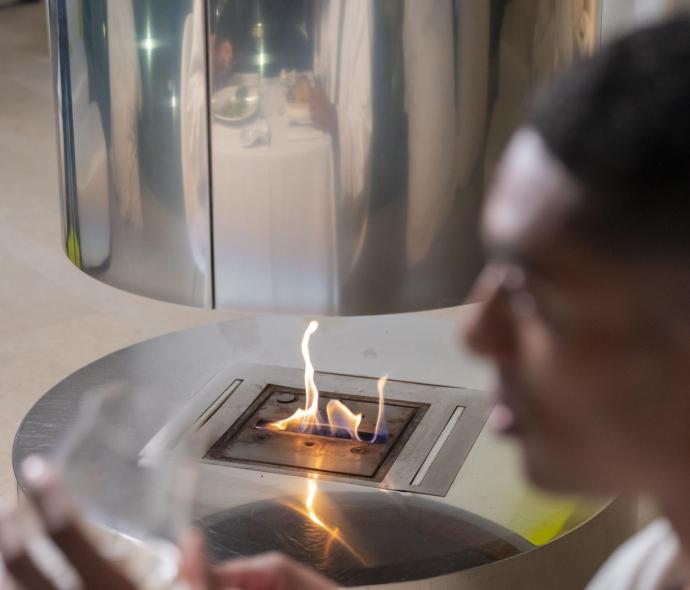 Man in a robe near a modern fireplace.