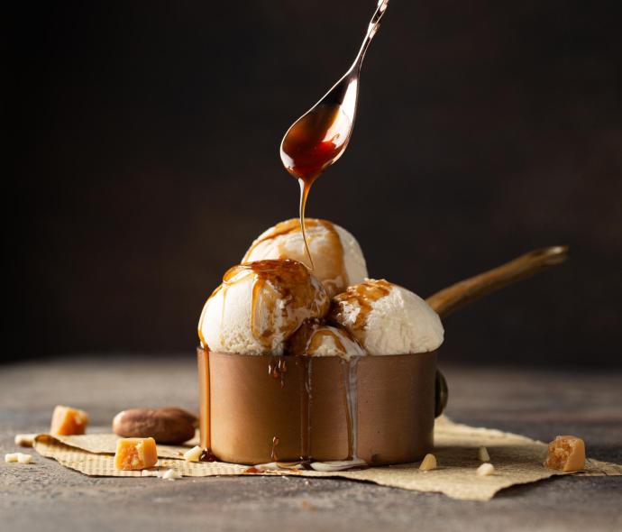 Gelato alla vaniglia con salsa al caramello in una ciotola di rame.